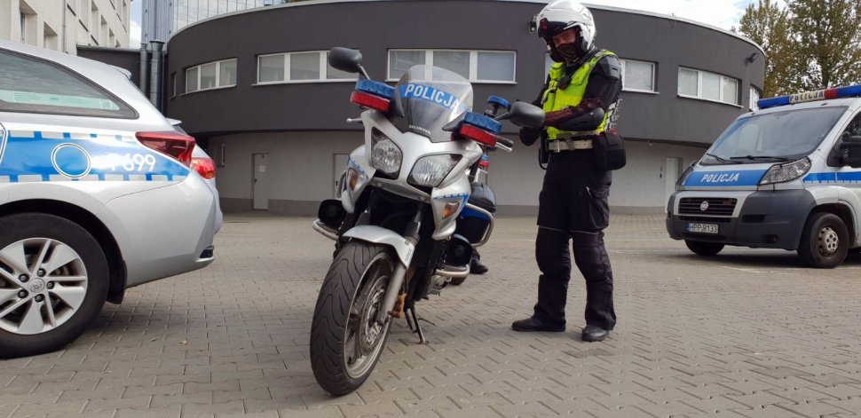 Policjant ruchu drogoweo przygotowuje się do służby na motocyklu.