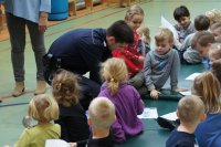 policjant ogląda z dziećmi kolorowanki