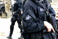 policjant gsr trzyma pistolet maszynowy. Widoczna naszywka na ramieniu gsr śląsk. w tle idzie drugi policjant gsr oraz stoi żołnierz