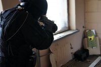 policjant w mundurze ćwiczebnym i kasku celuje bronią do tarczy w pomieszczeniu