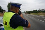 policjant dokonuje pomiaru prędkości przy drodze