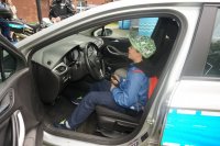 Dziecko - chłopiec w policyjnym radiowozie na miejscu kierowcy.