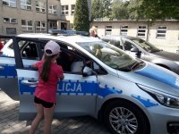 Radiowóz i dzieci oglądające samochód policyjny.