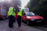 2 policjantów drogówki wykonuje czynności na miejscu wypadku. obok czerwony opel corsa