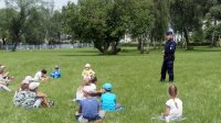 Dzieci słuchają porad policjanta w ramach akcji policyjnej.