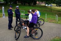 dwóch policjantów rozdaje odblaski 4  chłopcom na rowerach