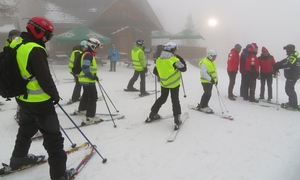 Grupa osób ubrana w kurtki zimowe i kaski na nartach.